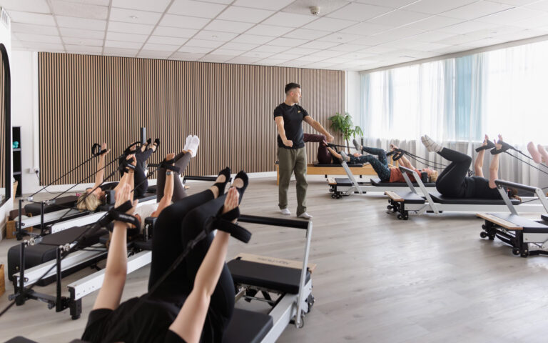 A pilates class taking place with a man leading the session